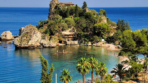 A coastal view with a rocky island, clear blue sea, and a building on top. - Belvilla by OYO Villa Trecastagni (Trecastagni)