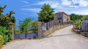 A rural road leading to a stone building with a tiled roof, surrounded by greenery and fences. - Lavish Sicilian Villa With Pool (Ficarra)
