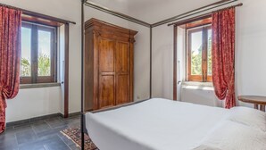 A bedroom with a bed, a wooden wardrobe, and two windows with curtains. - Lavish Sicilian Villa With Pool (Ficarra)