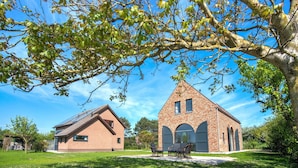A brick building with a triangular roof, a smaller attached structure, and a tree in the foreground.