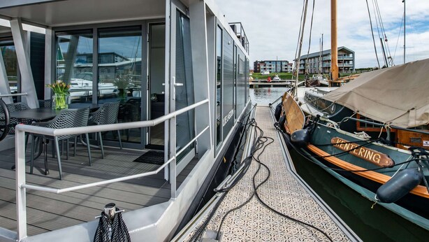 Un bateau moderne doté d’un espace de pont couvert, de grandes fenêtres et de sièges extérieurs.