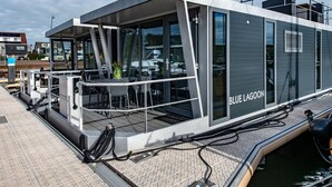 Une structure flottante moderne appelée « Blue Lagoon », dotée d’un espace extérieur couvert et de grandes fenêtres.