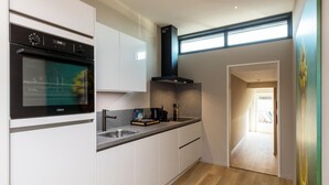 Une cuisine moderne avec des meubles blancs, un four noir et une fenêtre au-dessus de l’évier.