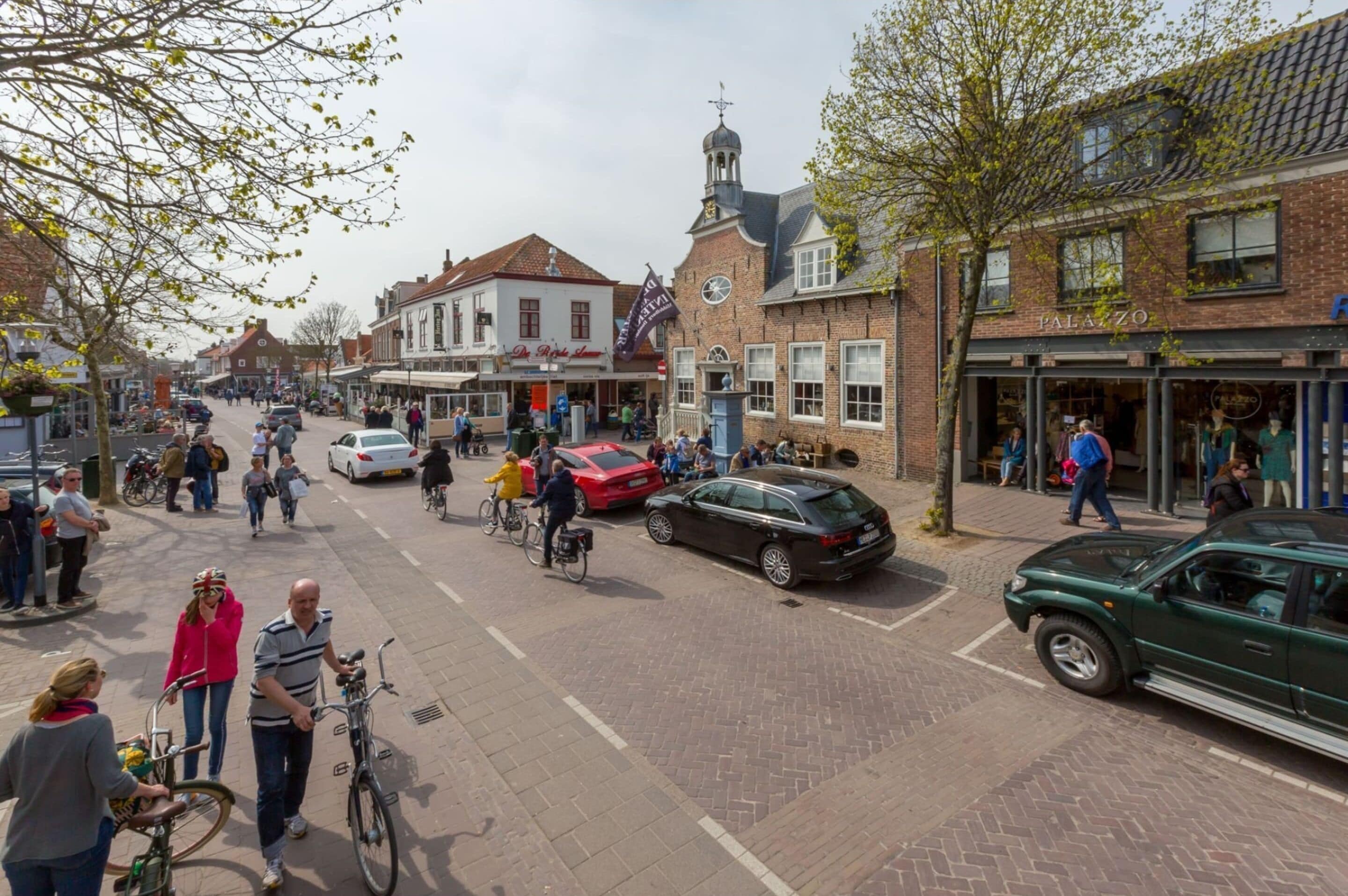 A street scene with pedestrians, bicycles, and cars.