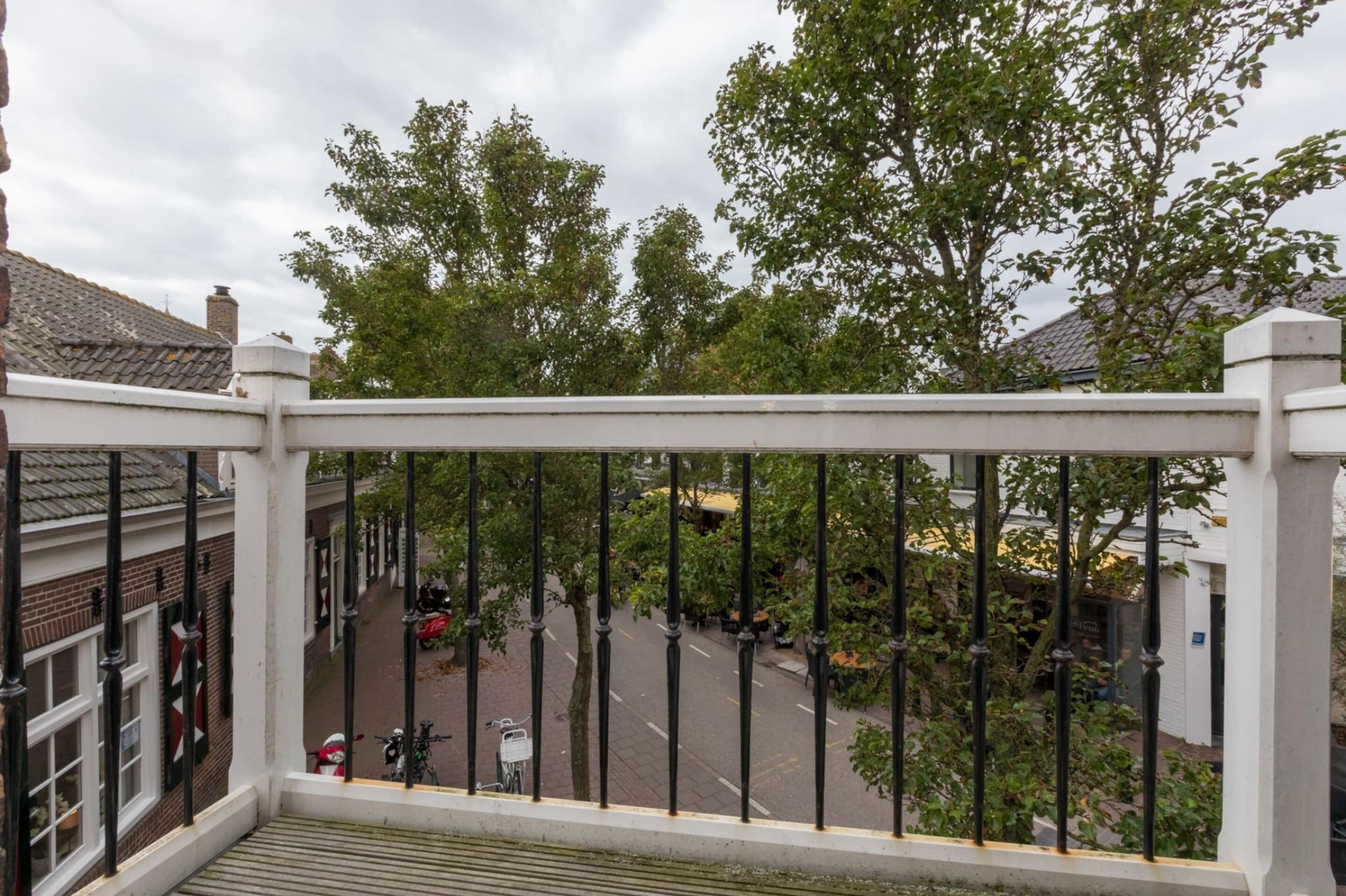 Ein Balkon mit Blick auf eine Straße, Bäume und Gebäude.