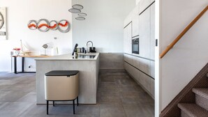 A modern kitchen with a central island, a built-in oven, and a stainless steel sink. - Spacious Flat With Views of the Harbour (Ouddorp)