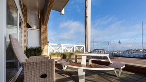 A patio with wicker furniture, a table, and a view of the marina. - Spacious Flat With Views of the Harbour (Ouddorp)
