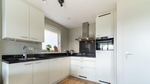 Uma cozinha moderna com armários brancos, bancada preta e exaustor de aço inoxidável.