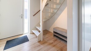 Um interior moderno com piso de madeira, uma porta branca e uma escada em espiral.