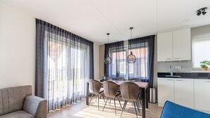 Uma sala de estar moderna com um sofá, uma cadeira azul e um espaço de refeições com mesa e cadeiras.