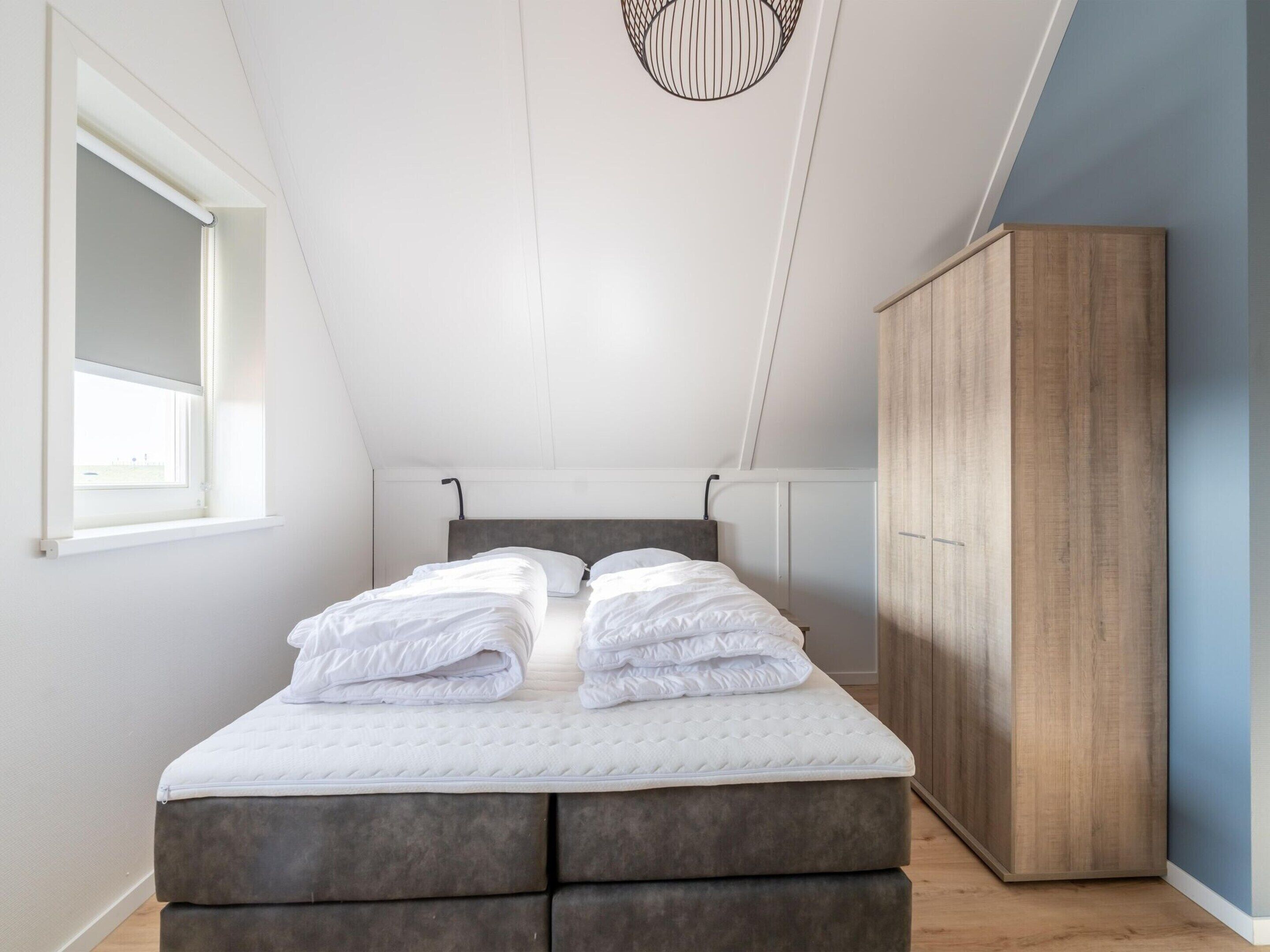 Un dormitorio con cama, armario y ventana.
