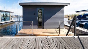 Ein modernes Boot mit Holldeck und einer kleinen Kabine mit Glastür.