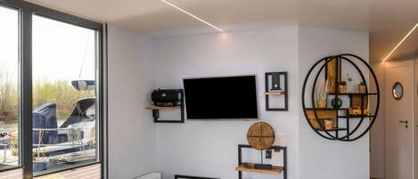 Una sala de estar moderna con un amplio ventanal, un televisor de pantalla plana y estanterías empotradas.