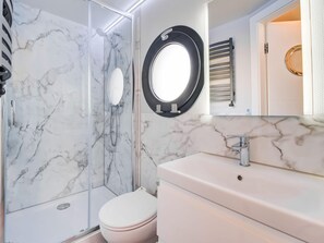 Un bany amb plat de dutxa de marbre, vàter i un lavabo amb mirall a la part superior.