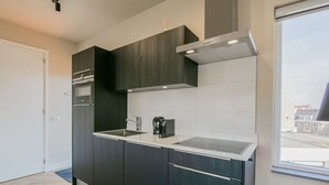 Une cuisine moderne avec des meubles de couleur sombre, un évier en acier inoxydable et une fenêtre donnant sur la ville.