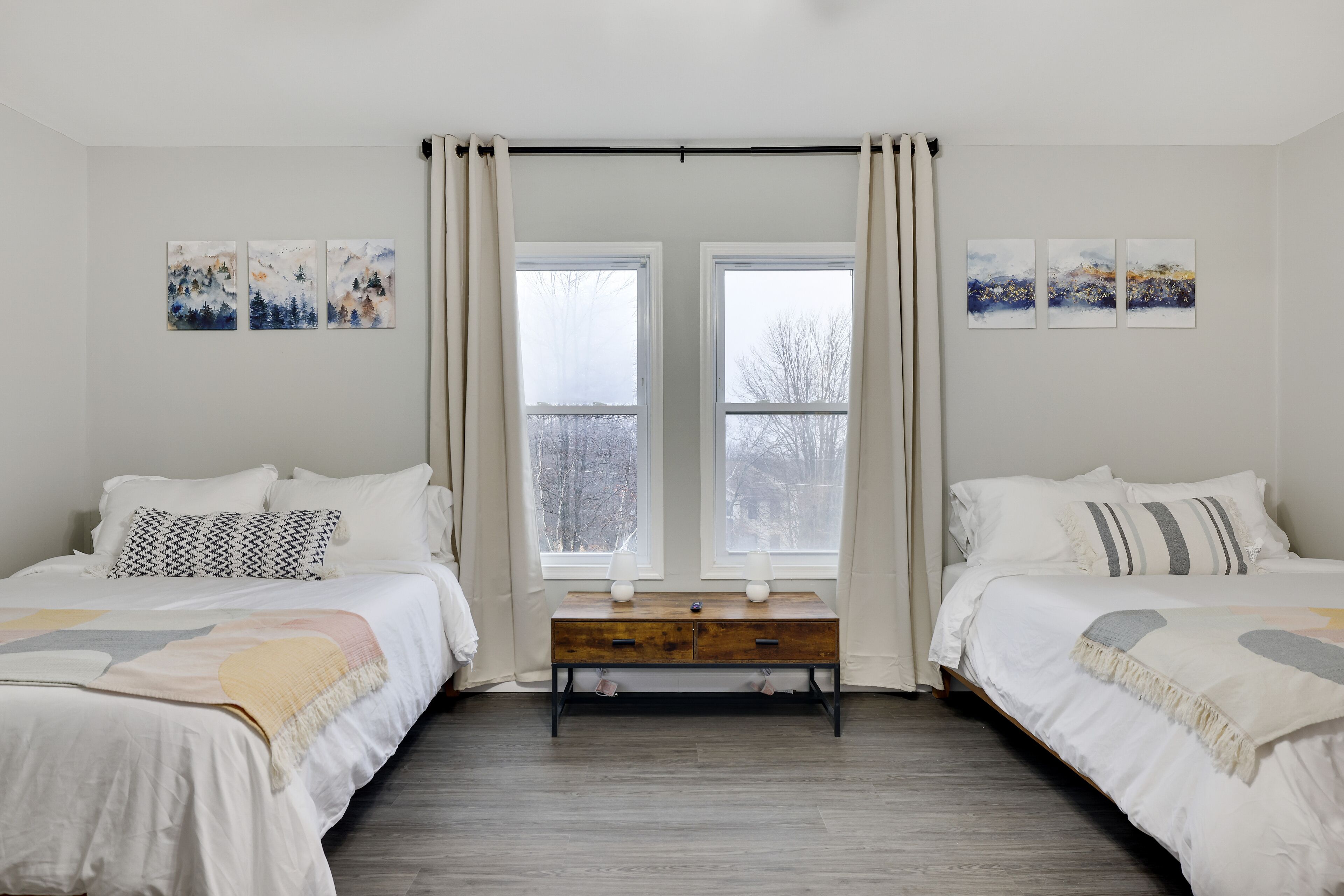 Una camera da letto con due letti, una panca di legno e opere d'arte alle pareti.