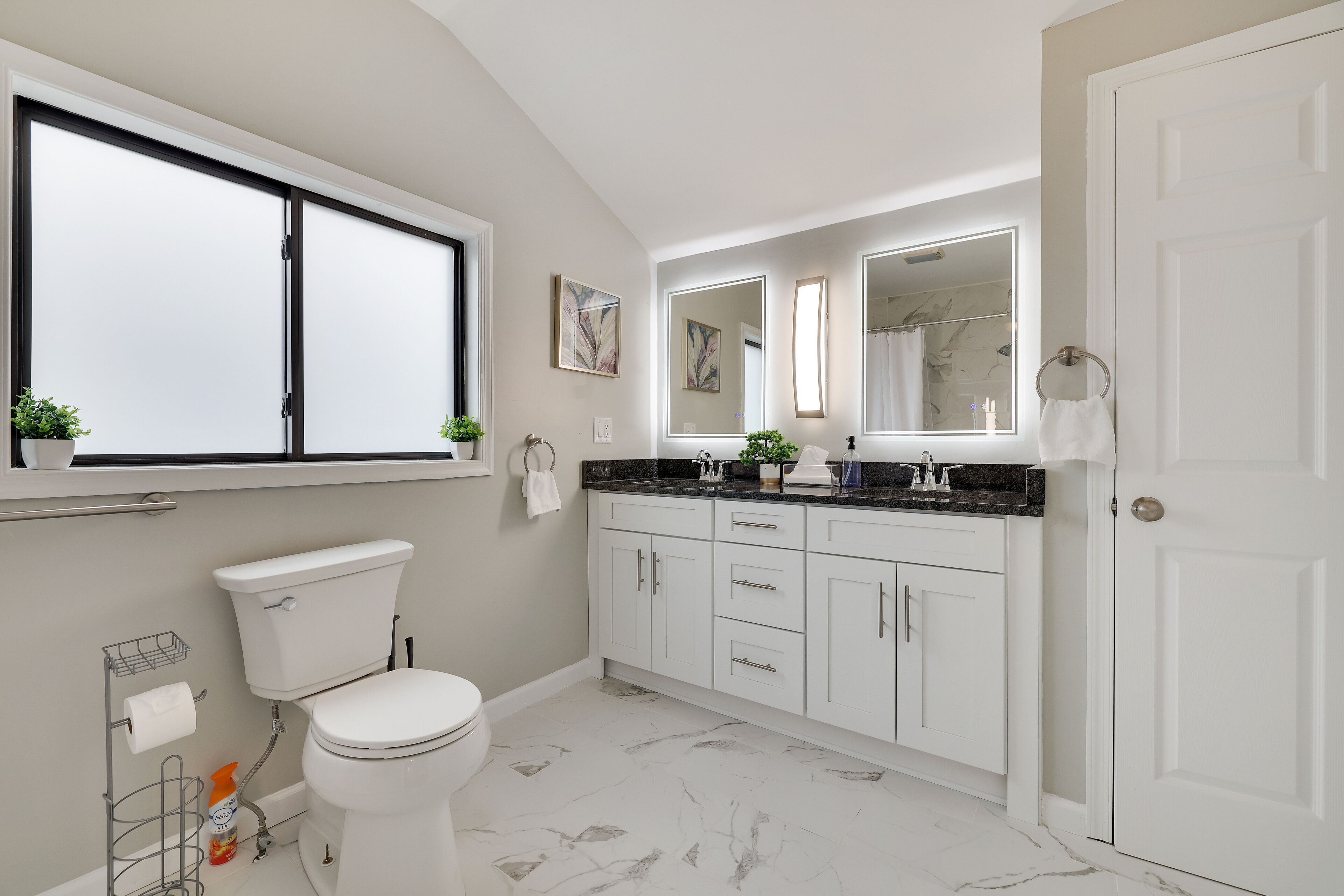Een moderne badkamer met toilet, wastafel en spiegel.