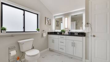 Een moderne badkamer met toilet, wastafel en spiegel.