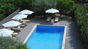 A rectangular swimming pool surrounded by lounge chairs and white umbrellas, with a brick pathway leading to it. - Apt Villa for Families (Santa Venerina)