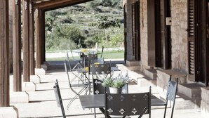 An outdoor patio with tables and chairs, a pergola, and a view of a hilly landscape. - Belvilla by OYO Acanto Bilocale (Modica)