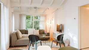 A modern living room with a sofa, two armchairs, a coffee table, and a TV.