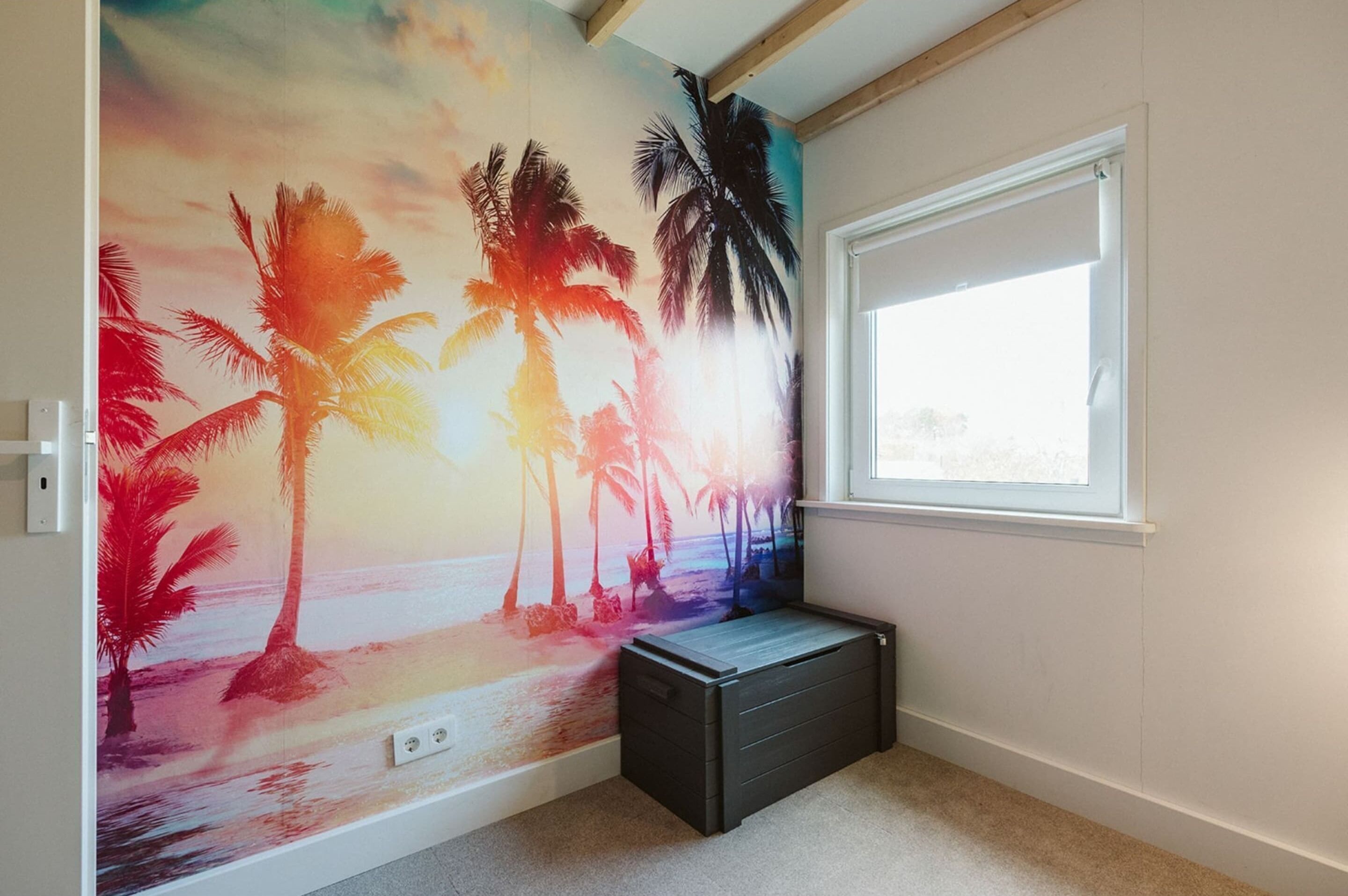 A room with a beach mural, a window, and a black storage unit.