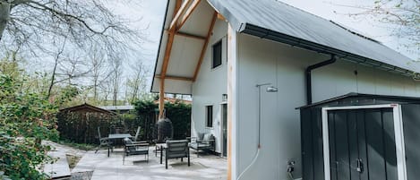 A modern house with a sloped roof, a patio with outdoor furniture, and a shed.