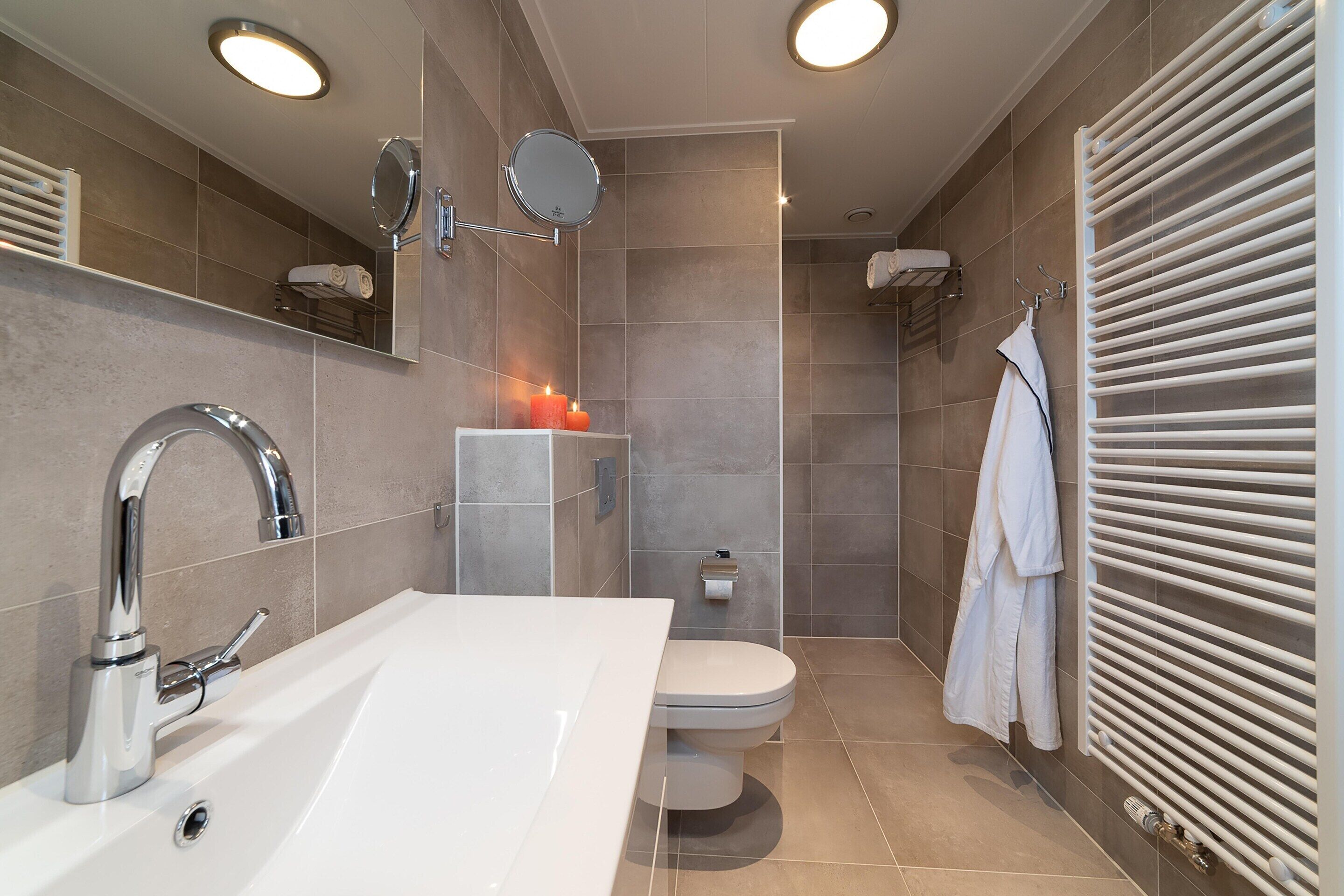 Une salle de bain moderne avec un lavabo blanc, des toilettes et un espace douche.