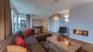 A modern living room with a sectional sofa, a coffee table, and a fireplace. - Villa in Colijnsplaat by the Sea & Sauna (Colijnsplaat)