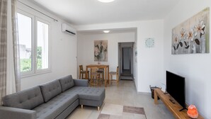 A modern living room with a grey sectional sofa, a wooden coffee table, and a flat-screen TV on a wooden stand.