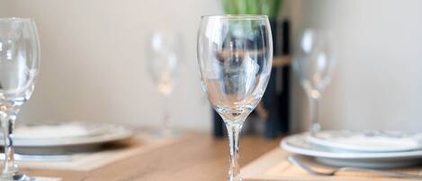 A dining table with a clear glass wine glass in the center, surrounded by plates and cutlery.