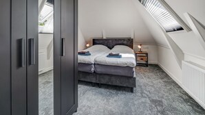 A bedroom with a sloped ceiling, a bed, a nightstand, and a wardrobe. - Stylish Farmhouse With Spa Tub (Kootstertille)