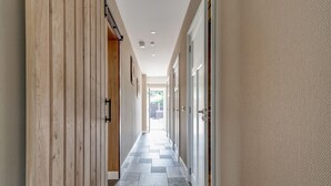 A hallway with wooden paneling on one side and a textured wall on the other. - Stylish Farmhouse With Spa Tub (Kootstertille)
