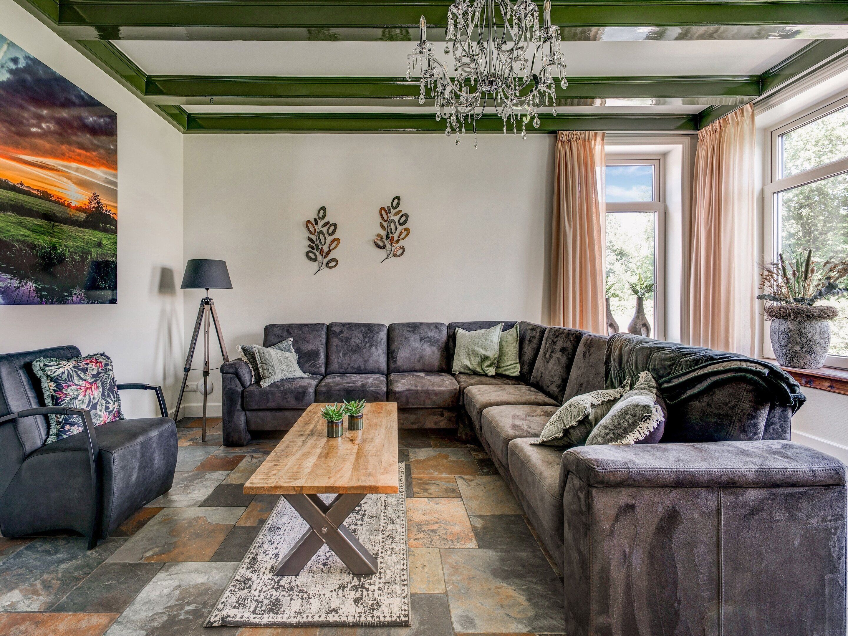 A modern living room with a sectional sofa, a wooden coffee table, and a chandelier.