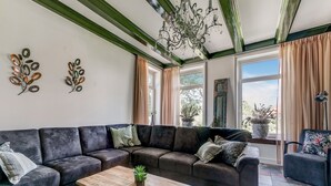 A modern living room with a sectional sofa, a wooden coffee table, and a chandelier. - Stylish Farmhouse With Spa Tub (Kootstertille)