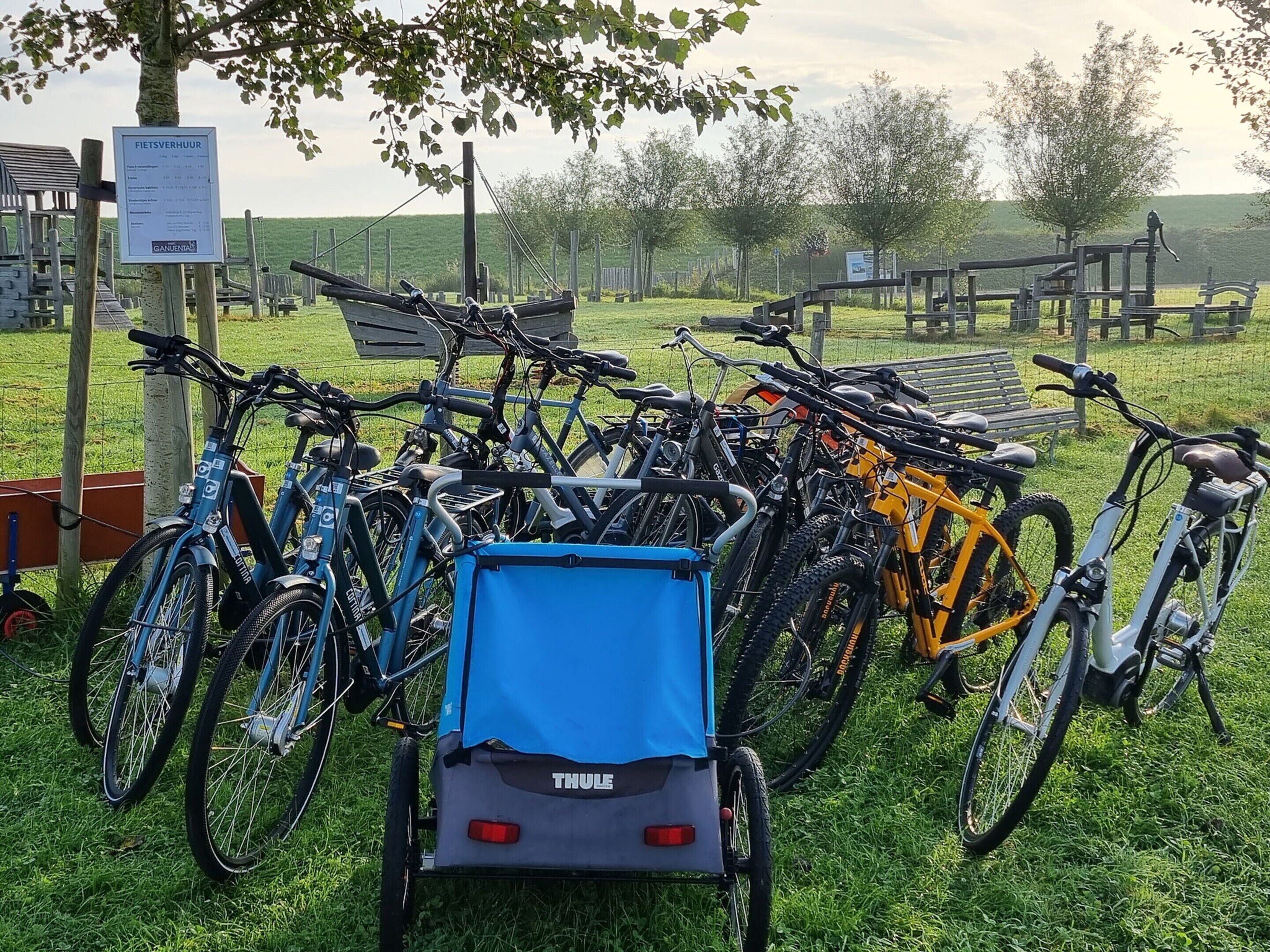Bicycles parked in an outdoor area with a blue Thule bike carrier.