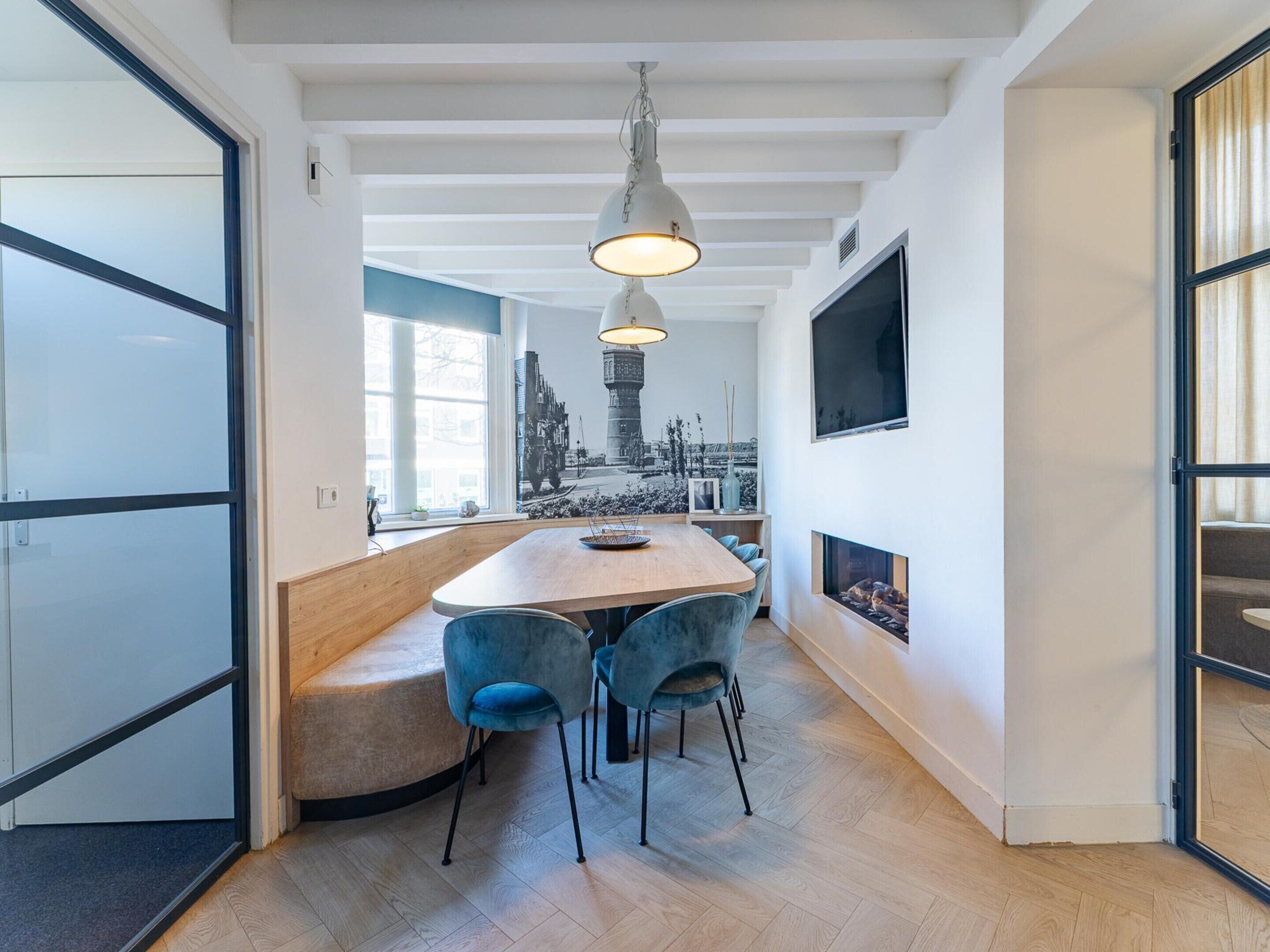 Een moderne keuken met een houten kookeiland, blauwe stoelen en een hanglamp.