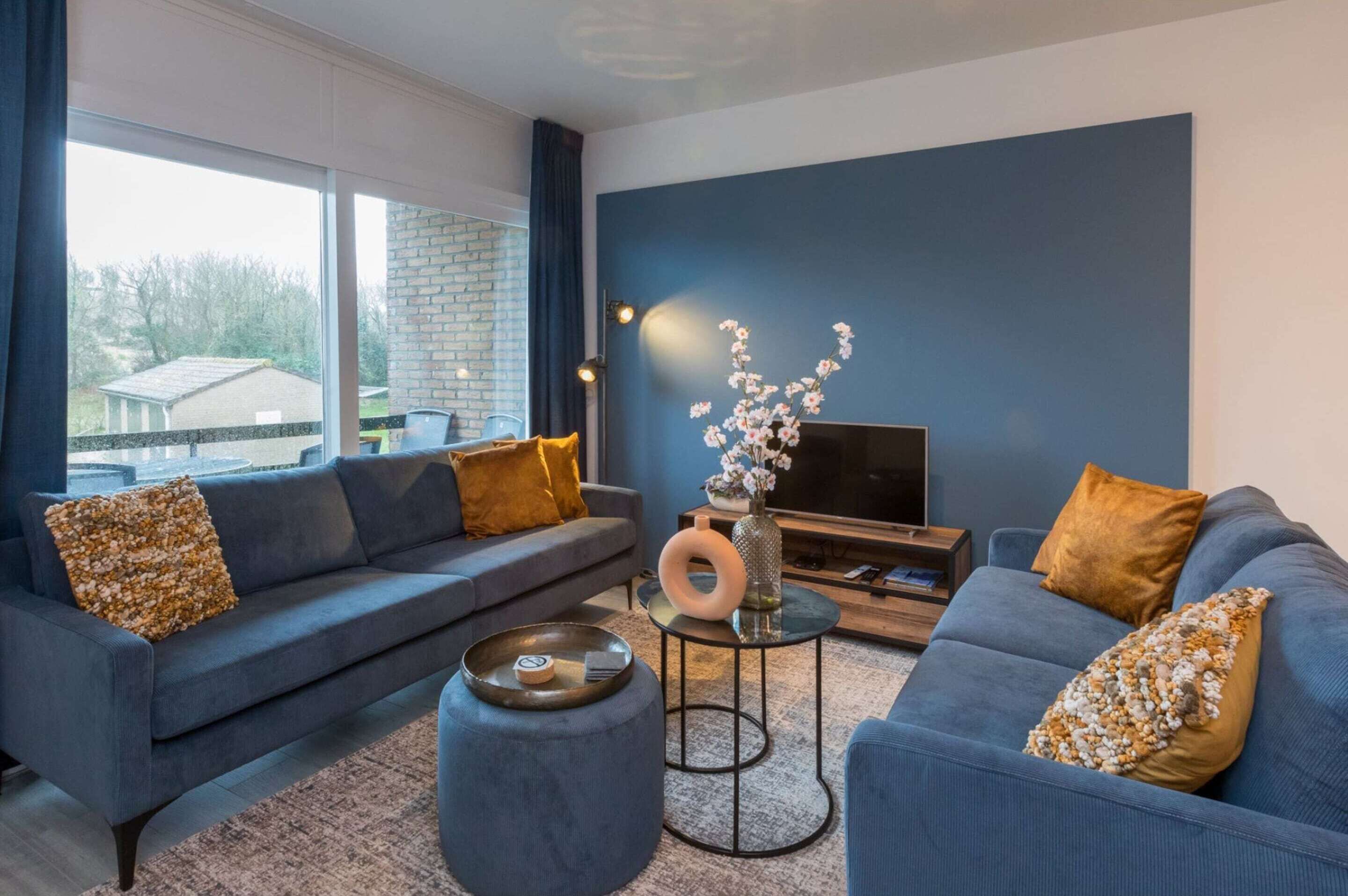 Ein modernes Wohnzimmer mit einer Couch, einem Hocker und einem kleinen Tisch mit einer Vase.
