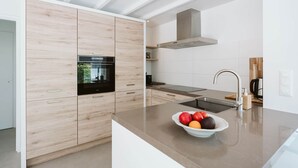 Eine moderne Küche mit Holzschränken, einem eingebauten Backofen und einer Spüle aus Edelstahl.