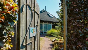 A wooden gate with a rope, leading to a house with a sloped roof and a window. - Lovely Holiday Home 10 Minutes by Bike (Ouddorp)