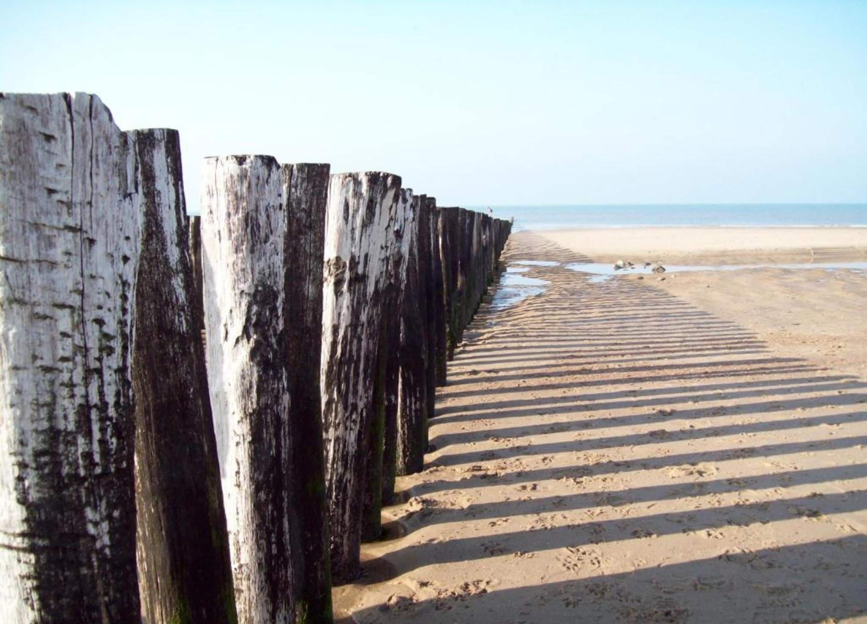 A wooden boardwalk leading to a beach with a clear view of the ocean.