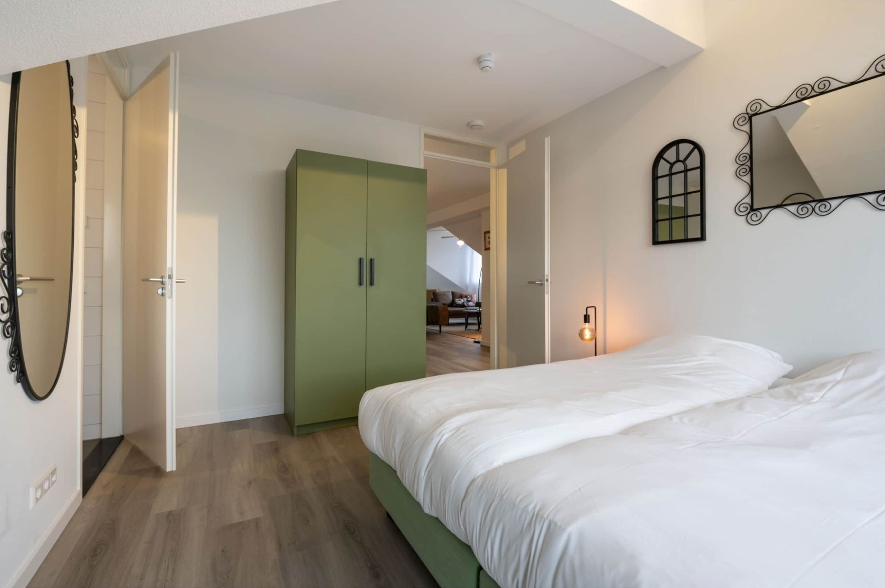 A bedroom with a bed, a wardrobe, and a mirror on the wall.