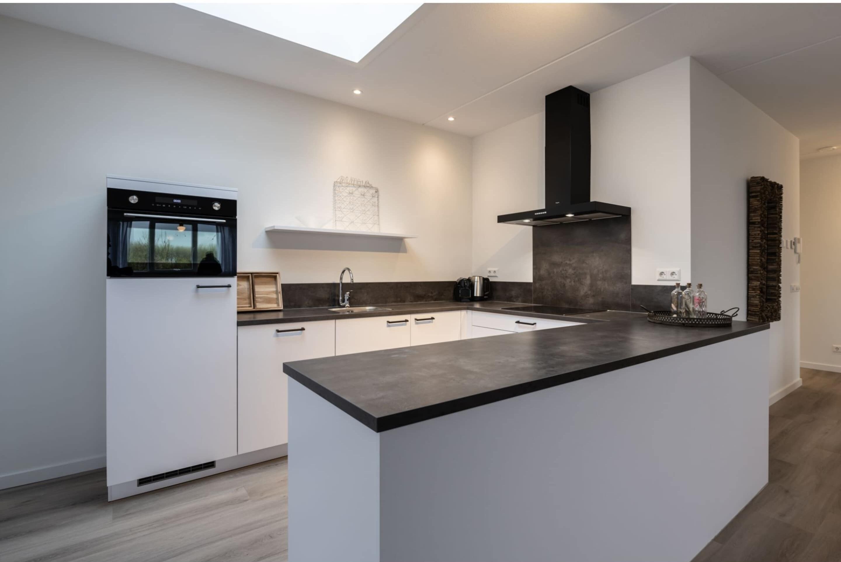 A modern kitchen with white cabinets, a black countertop, and a built-in oven.