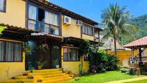 A yellow building with a tiled roof, air conditioning units, and a small porch with steps leading to the entrance. - Relax and enjoy recess time (RIO DE JANEIRO)