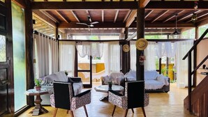 A spacious room with a wooden ceiling, a sofa, two patterned chairs, a small table with a plant, and a staircase. - Relax and enjoy recess time (RIO DE JANEIRO)