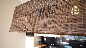 A kitchen with white cabinets, a black countertop, and a wicker hanging light fixture. - Modern Apartment Overlooking the Harbor (The Hague)