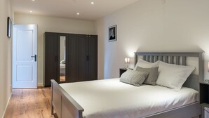 A bedroom with a bed, nightstands, a wardrobe, and a door. - Detached new 10-person Villa in Holiday Park (Kamperland)