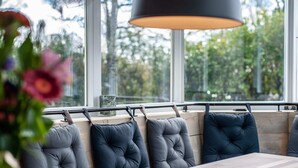 A modern dining area with a long wooden table and cushioned seating. - Detached new 10-person Villa in Holiday Park (Kamperland)