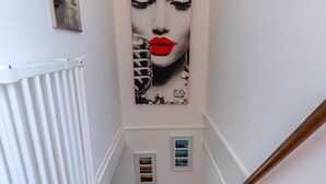 A staircase with a handrail, carpeted steps, and a wall-mounted artwork. - Holiday Home in the Middle of the Green North Sea Park Near the Beach Entrance (Ouddorp)