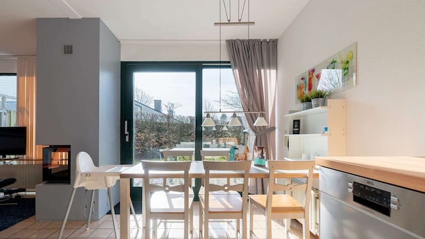 A modern kitchen with a dining area, a large window, and a view of the outdoors. - Holiday Home in the Middle of the Green North Sea Park Near the Beach Entrance (Ouddorp)